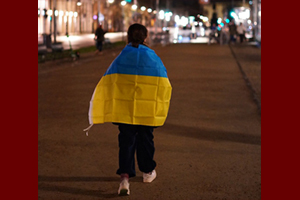 Frau auf einer Straße mit einer umgehängten Ukraine-Fahne