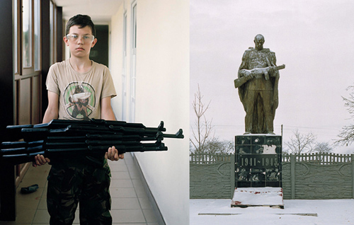Ein Junge mit Gewehr in den Händen; daneben eine Statue mit Gewehr