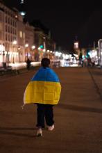 Frau auf einer Straße mit einer umgehängten Ukraine-Fahne